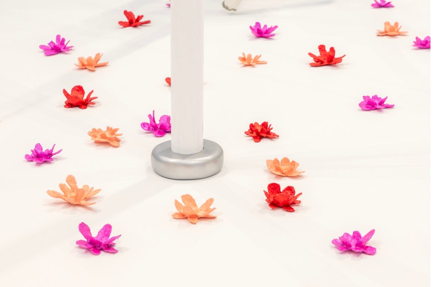 Tip of white cane sculpture arising from a field of peach, red, and magenta flowers